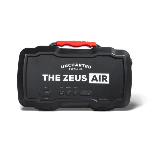 A black portable jump starter/inflator device with 'THE ZEUS AIR' written on it, featuring red and silver accents, various buttons and ports, and a carrying handle.