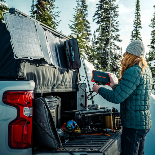 Dark Energy Poseidon XL portable power bank charging from solar panels in snowy truck bed