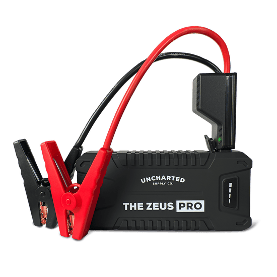 Uncharted Supply Co. Zeus Pro portable car jump starter with red and black booster cables and clamps