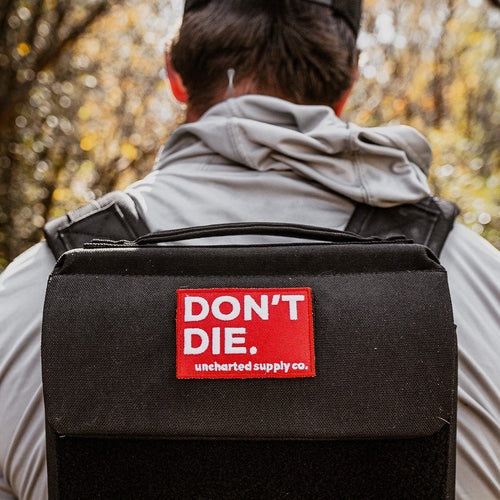 DON'T DIE Velcro Patch on a black tactical backpack, essential survival gear for outdoor adventures