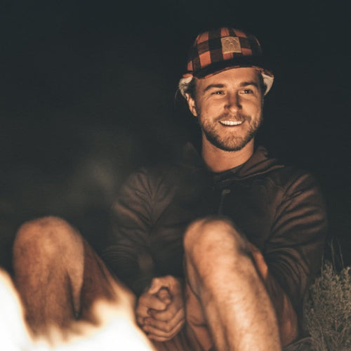 HWY8 Hat, a red and black plaid bucket hat, worn by man by campfire at night