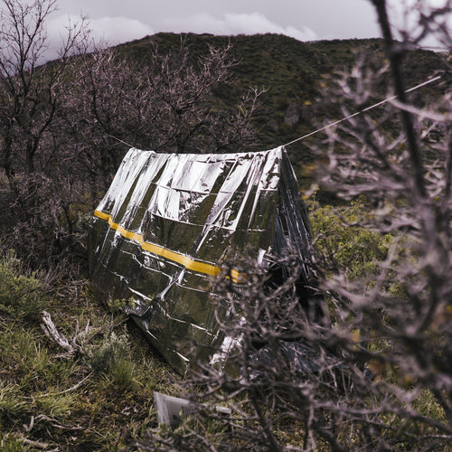 Survival Tent, thermal emergency bivvy with yellow stripe in a wilderness setting