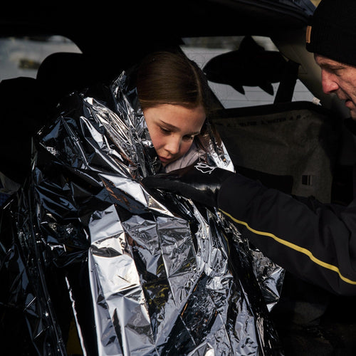 Mylar Emergency Blanket providing warmth to a child, an adult in survival gear offers cold weather comfort