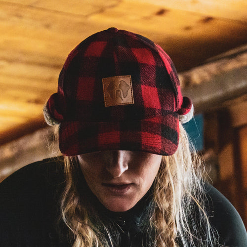 HWY8 Hat, red & black buffalo plaid trapper hat with ear flaps & leather logo patch, worn by a person