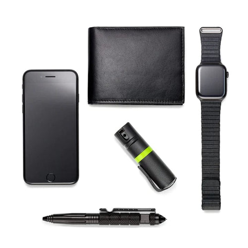 POM Pepper Spray, black personal safety device with green band, shown with EDC items for scale